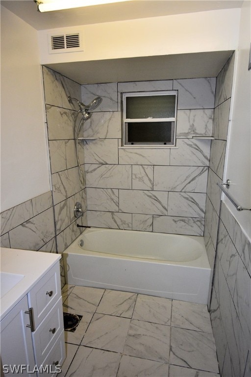 bathroom with vanity, tiled shower / bath, and tile walls