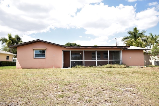 rear view of house featuring a yard and a sunroom