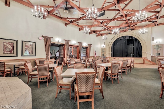 carpeted dining area featuring a high ceiling and beam ceiling