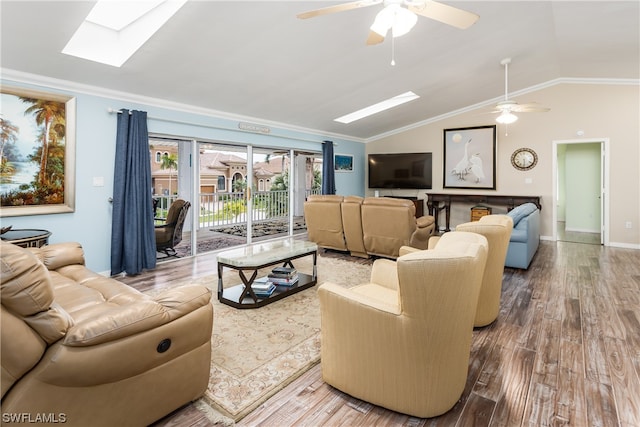 living room featuring hardwood / wood-style floors, vaulted ceiling with skylight, crown molding, and ceiling fan