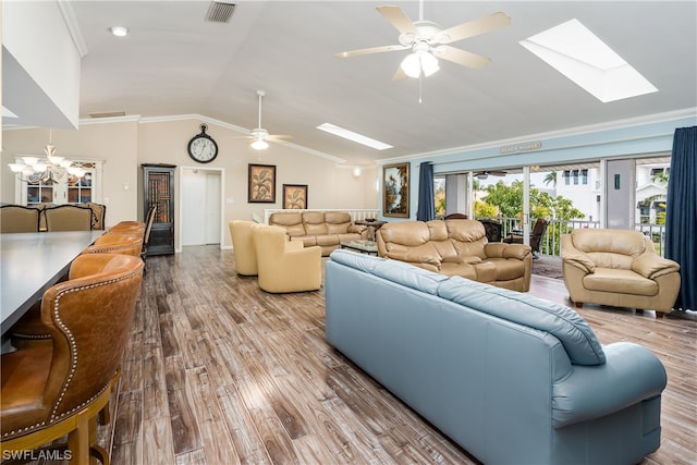 living room with vaulted ceiling with skylight, ornamental molding, light hardwood / wood-style flooring, and ceiling fan with notable chandelier