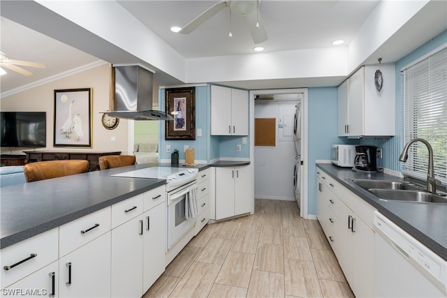 kitchen with white appliances, ceiling fan, stacked washer / drying machine, white cabinets, and wall chimney range hood