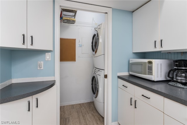 washroom featuring stacked washer and clothes dryer and light hardwood / wood-style flooring