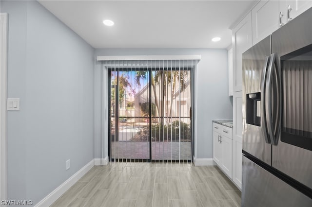 kitchen featuring white cabinets, stainless steel fridge with ice dispenser, and stone countertops