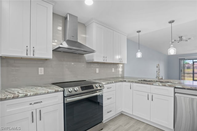 kitchen with pendant lighting, stainless steel appliances, wall chimney range hood, tasteful backsplash, and light stone counters