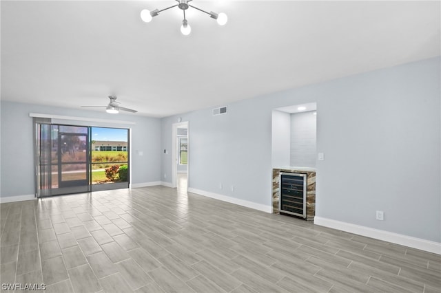 unfurnished living room with wine cooler and ceiling fan with notable chandelier