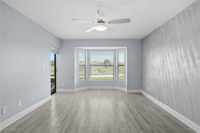 empty room with ceiling fan and light hardwood / wood-style flooring