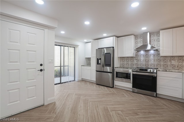 kitchen with wall chimney range hood, white cabinetry, backsplash, and appliances with stainless steel finishes