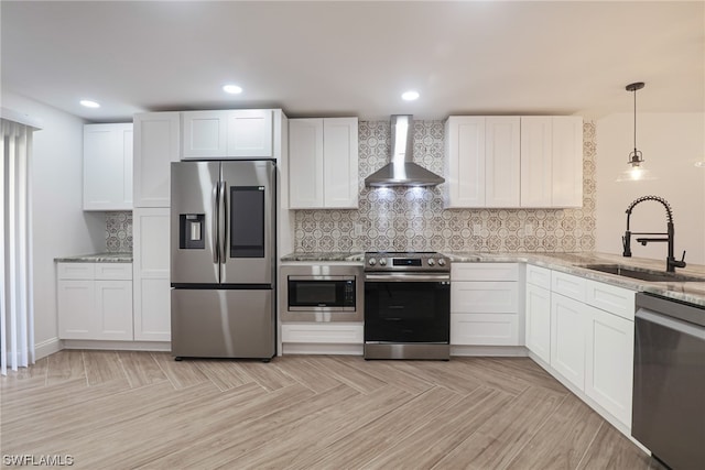 kitchen featuring wall chimney range hood, white cabinetry, and appliances with stainless steel finishes