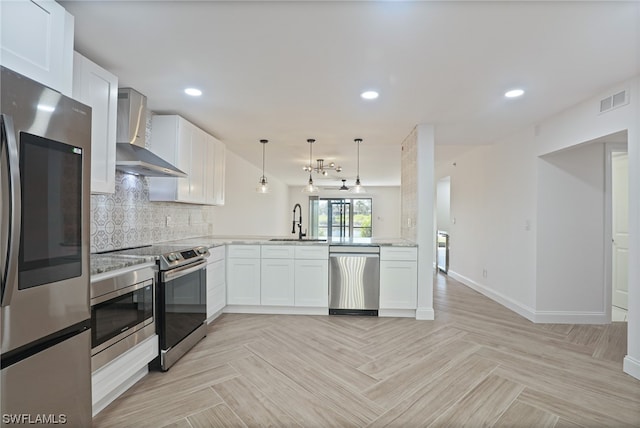 kitchen with kitchen peninsula, sink, white cabinets, appliances with stainless steel finishes, and wall chimney range hood