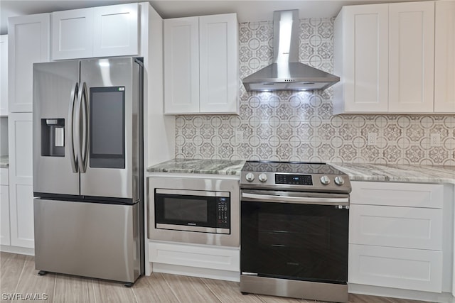 kitchen with wall chimney range hood, tasteful backsplash, and appliances with stainless steel finishes