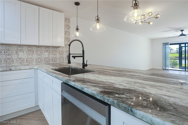 kitchen featuring light stone countertops, decorative light fixtures, stainless steel dishwasher, and sink