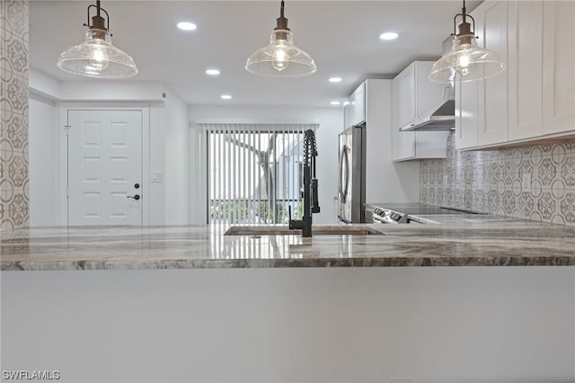 kitchen with decorative light fixtures, stainless steel fridge, white cabinets, light stone counters, and tasteful backsplash