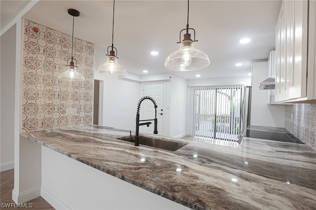 kitchen featuring sink, white cabinets, pendant lighting, and dark stone countertops