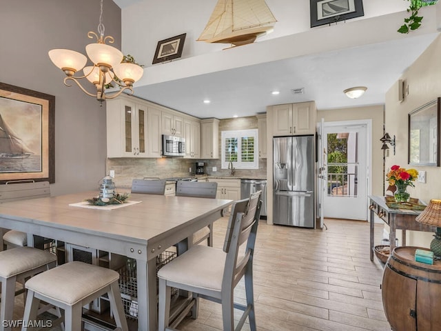 dining room featuring plenty of natural light, an inviting chandelier, sink, and light hardwood / wood-style flooring