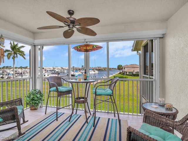 sunroom featuring a water view, ceiling fan, and plenty of natural light