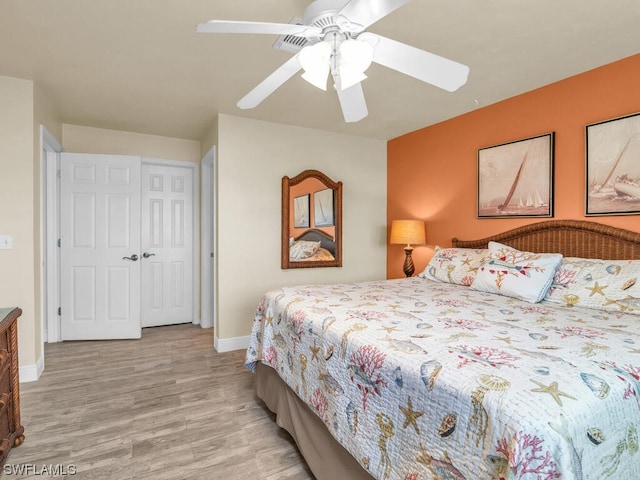 bedroom with a closet, light hardwood / wood-style floors, and ceiling fan