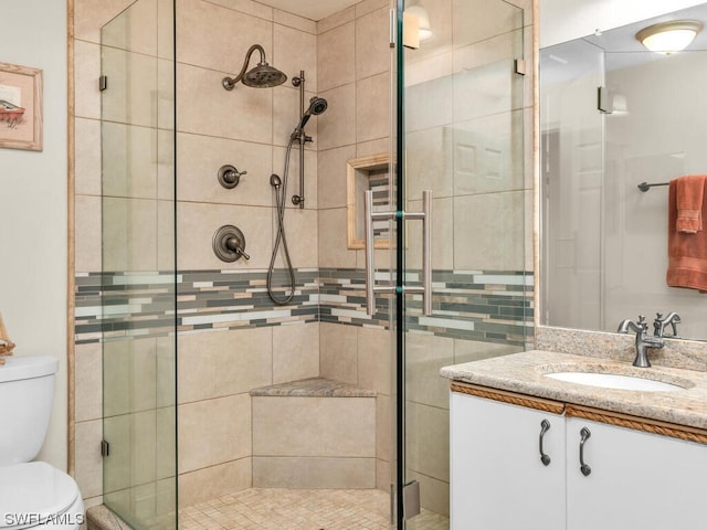 bathroom featuring an enclosed shower, vanity, and toilet