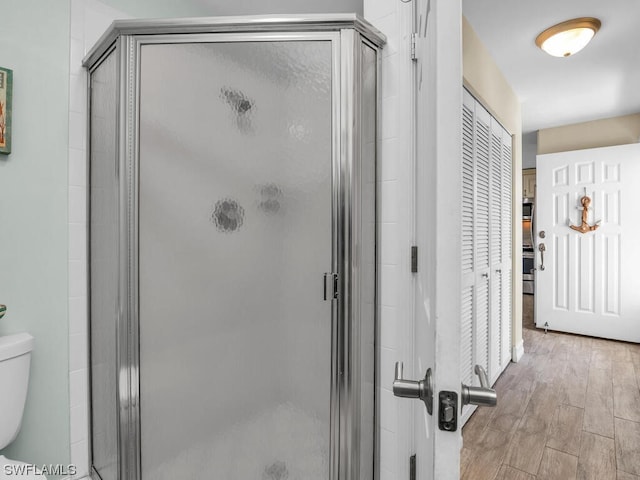 bathroom with toilet, hardwood / wood-style floors, and walk in shower