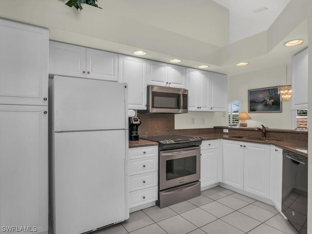 kitchen featuring white cabinets, backsplash, stainless steel appliances, light tile floors, and sink