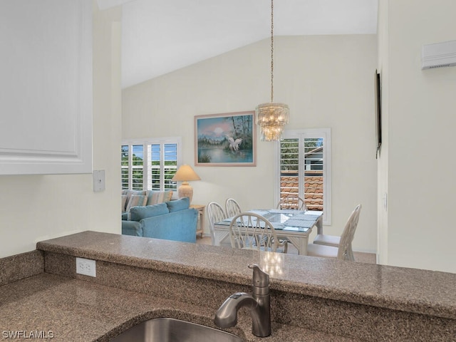 kitchen with white cabinets, hanging light fixtures, high vaulted ceiling, and an inviting chandelier