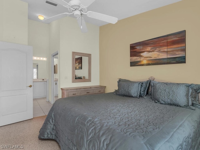 bedroom featuring ceiling fan, light carpet, ensuite bathroom, and a towering ceiling