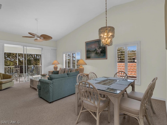 carpeted dining area featuring high vaulted ceiling, ceiling fan with notable chandelier, and a wealth of natural light