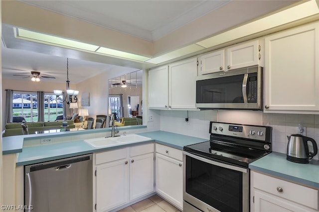 kitchen with stainless steel appliances, light tile flooring, ceiling fan with notable chandelier, white cabinets, and backsplash