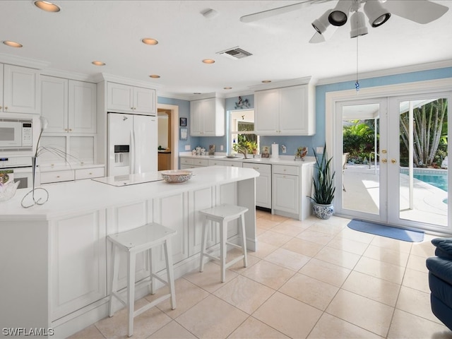 kitchen with white appliances, plenty of natural light, white cabinetry, and ceiling fan