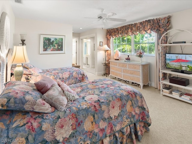 carpeted bedroom with ensuite bathroom and ceiling fan