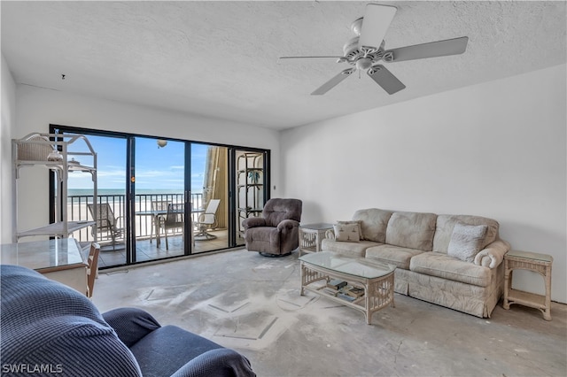 living room featuring a water view, ceiling fan, concrete flooring, and a textured ceiling