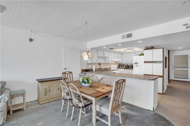 dining area with sink, a textured ceiling, and light tile floors