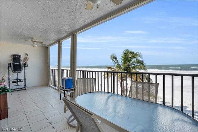 balcony with ceiling fan, a beach view, and a water view