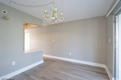 spare room featuring an inviting chandelier and hardwood / wood-style floors