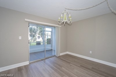 spare room featuring a chandelier and dark hardwood / wood-style flooring