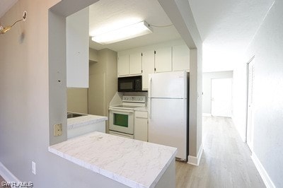 kitchen with range, white cabinetry, light wood-type flooring, and white refrigerator