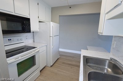 kitchen featuring white appliances, sink, white cabinets, light hardwood / wood-style floors, and light stone countertops