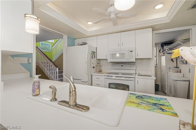 kitchen featuring a raised ceiling, white appliances, white cabinets, and ceiling fan