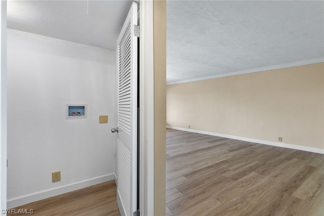 clothes washing area with wood finished floors, baseboards, ornamental molding, washer hookup, and laundry area