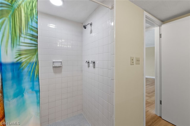 bathroom with wood finished floors and tiled shower