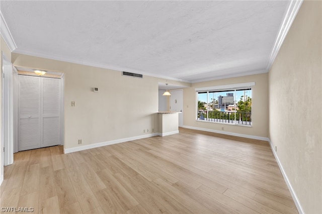 unfurnished living room featuring baseboards, visible vents, light wood-style floors, and crown molding