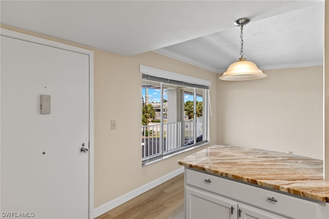 kitchen with light stone countertops, light wood-type flooring, white cabinetry, and hanging light fixtures