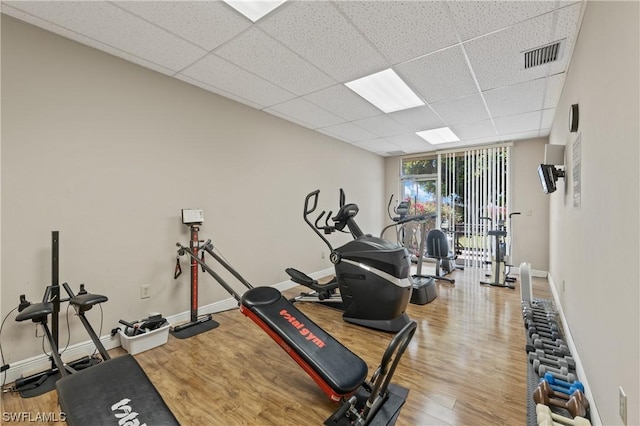 workout room with a wall of windows, visible vents, wood finished floors, and baseboards