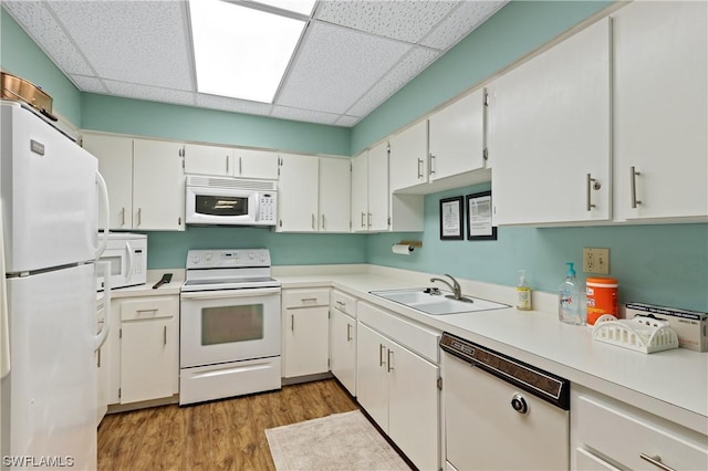 kitchen with a sink, light countertops, white cabinetry, and white appliances