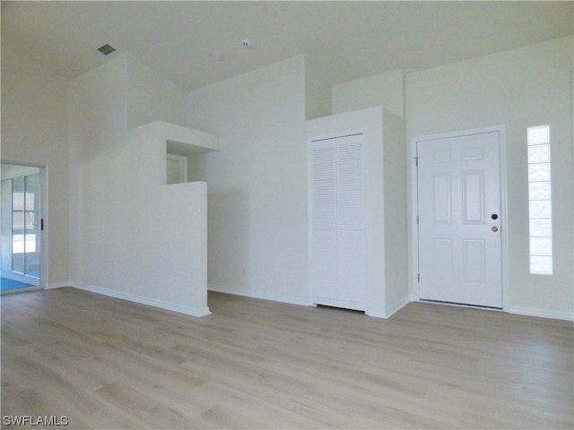 unfurnished room with a high ceiling and light hardwood / wood-style flooring