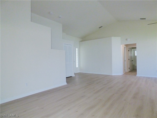 spare room with light wood-type flooring and vaulted ceiling