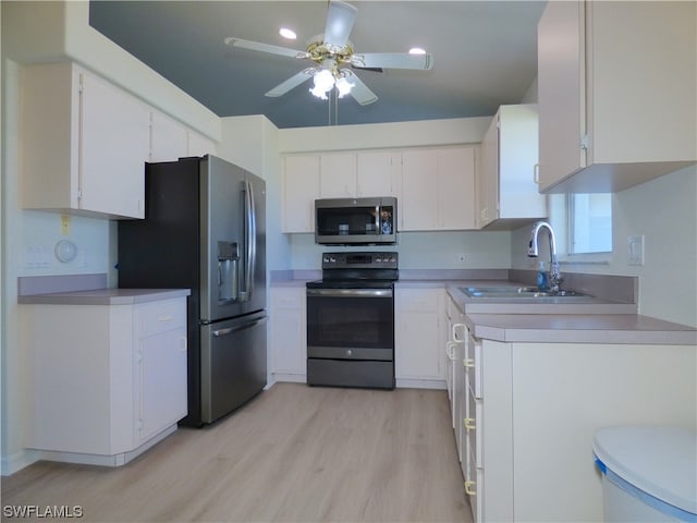 kitchen featuring stainless steel appliances, sink, white cabinetry, ceiling fan, and light hardwood / wood-style floors