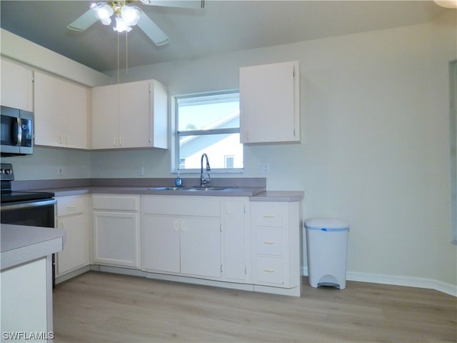 kitchen featuring stainless steel appliances, ceiling fan, white cabinets, light hardwood / wood-style flooring, and sink