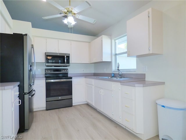 kitchen featuring appliances with stainless steel finishes, light wood-type flooring, ceiling fan, sink, and white cabinetry