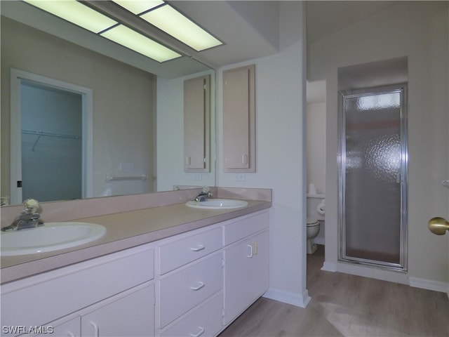 bathroom with toilet, a shower with door, vanity, and hardwood / wood-style floors